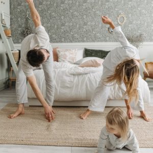 A family stretches together in a cozy bedroom, enjoying morning activities.